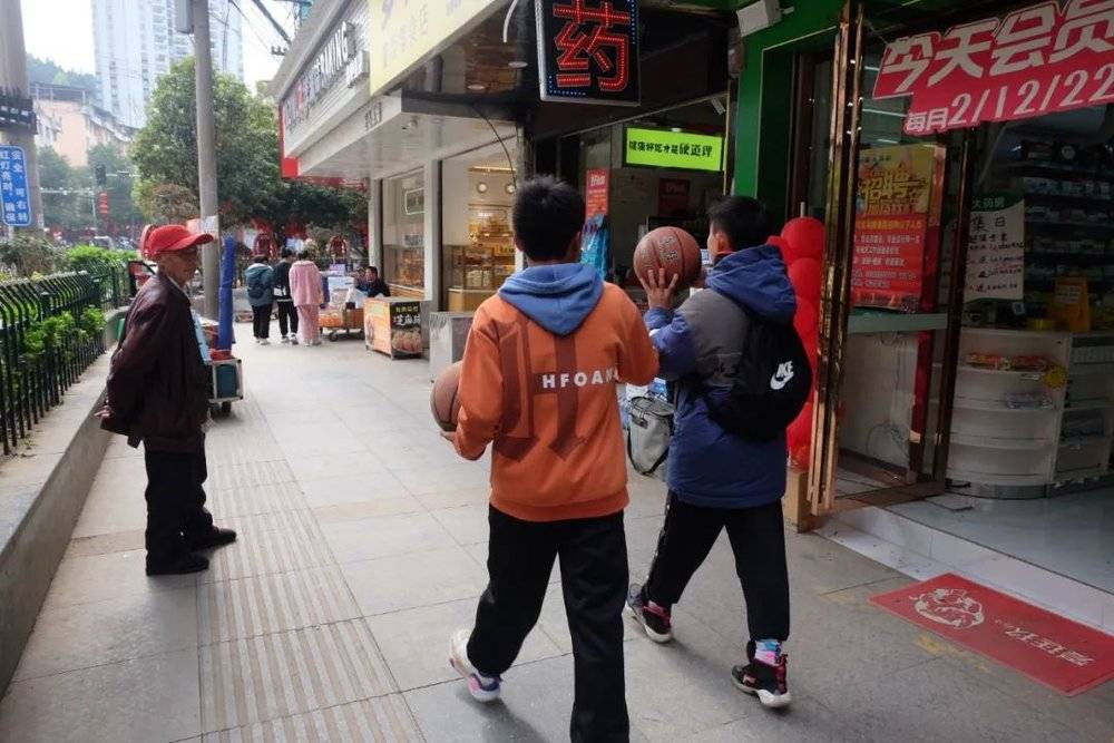台江县，一边走路一边玩篮球的学生。图/新周刊记者摄<br>