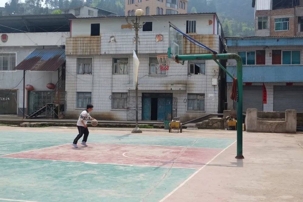 小小的凯棠乡有三个篮球场。其中一个球场上，一个男孩正独自练球。图/新周刊记者摄<br>