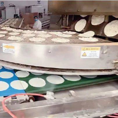 ▲岳川夫妇新购置的自动化机器正一刻不停生产小饼。农民日报·中国农网记者欧阳靖雯　摄
