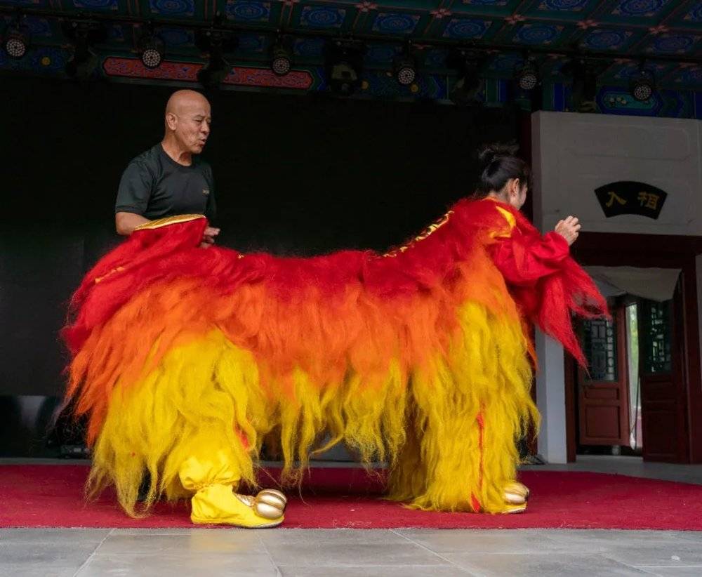 ■ 杨敬伟指导两名穿着狮裤狮鞋，披着狮囊的女狮队队员训练